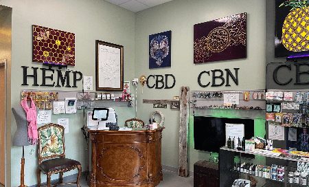 The retail floor: backlit honeycomb glass panels above the HEMP, CBD and CBN lettering, and the carved wooden counter